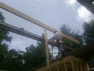 Carpenter setting a ridge beam over a new addition frame — Ice Dam Removal by Roofing Brothers in Melvin Village