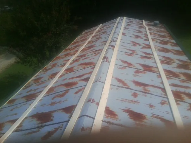 Rusted metal roof panels with new wood purlins before replacement — Storm Damage Roof Repair in Melvin Village by Roofing Brothers