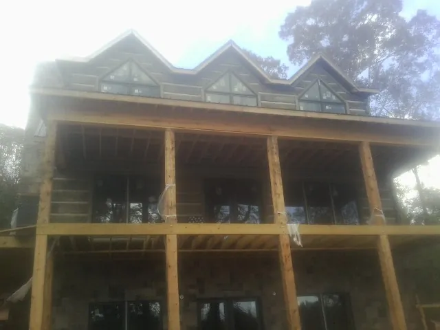 Dormers and porch framing on a large log home under construction — Roof Coating work by our crew in Melvin Village