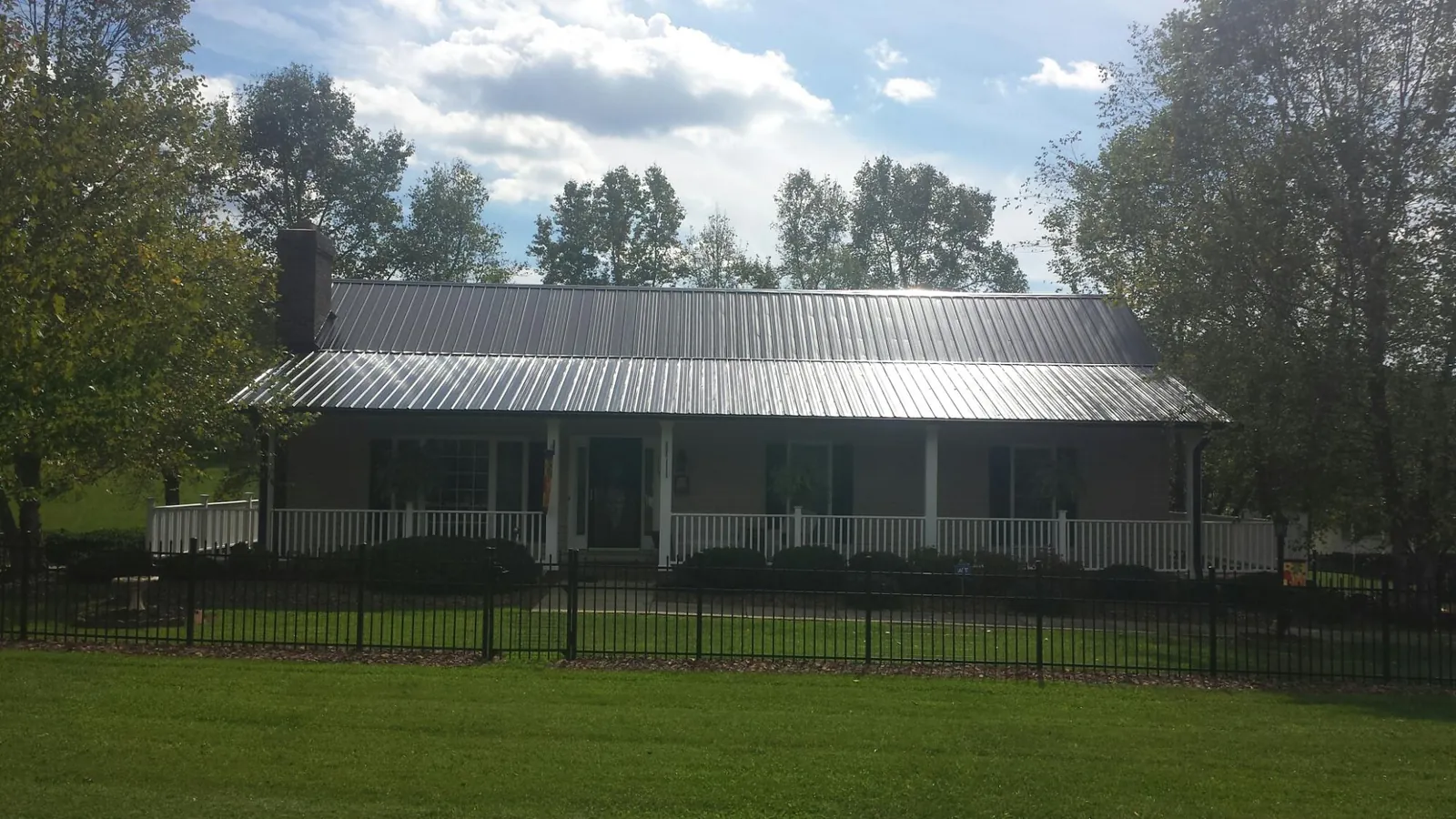 Gray metal roof on a brick ranch with a full width front porch — Gutter Guard Installation work by our crew in Melvin Village