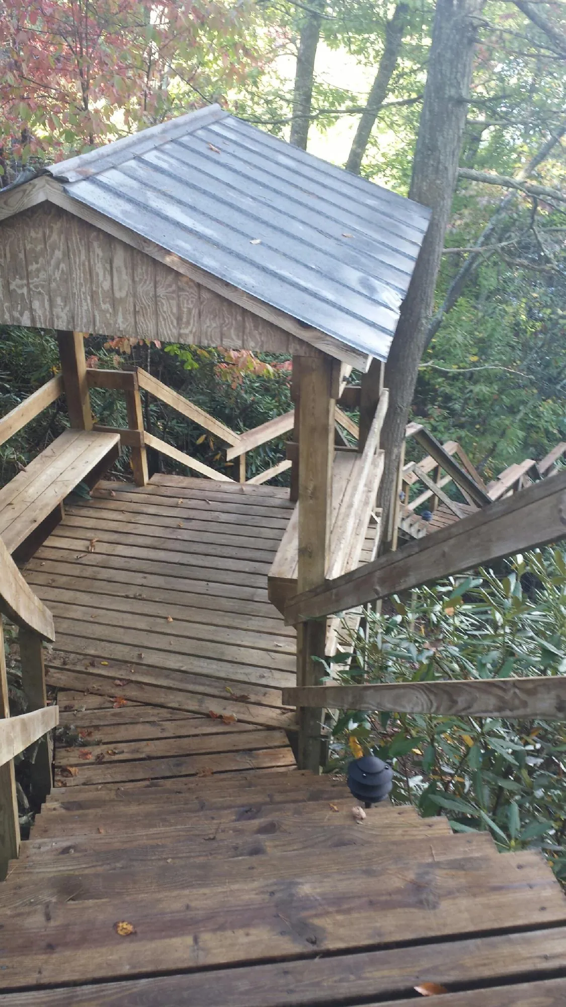 Metal roofed shelter over wooden steps on a wooded walkway — Skylight Repair & Installation work by our crew in Melvin Village