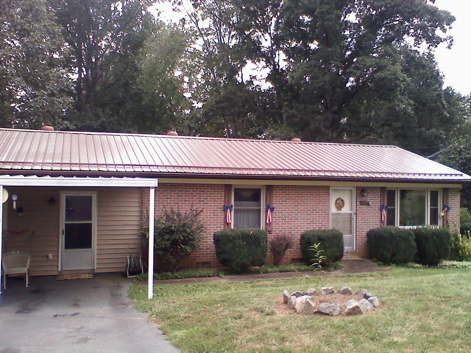 Bronze metal roof and carport on a brick ranch home — Roof Repair work by our crew in Melvin Village