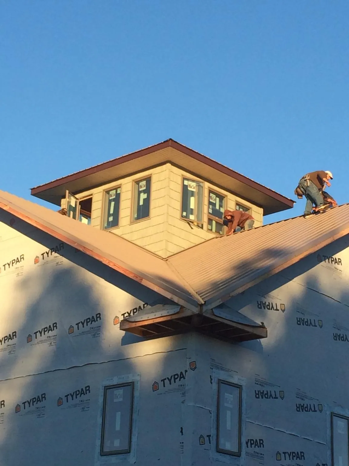 Roofers working around a rooftop cupola on a new metal roof at sunset — Roof Waterproofing in Melvin Village by Roofing Brothers